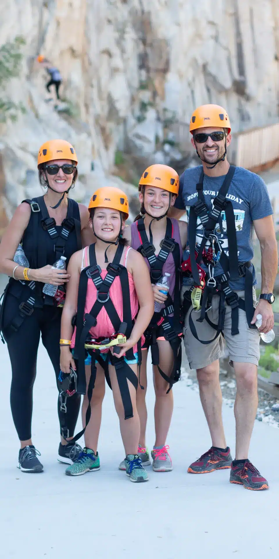 A family of four wearing helmets and harnesses smiles outdoors, ready for adventure—perhaps ziplining or climbing. This could be the perfect 2025 Hero moment for those seeking excitement close to home.