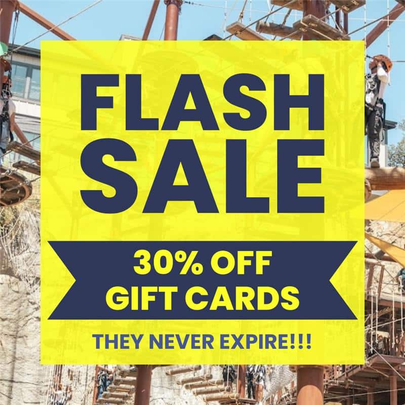 Yellow banner with text: "FLASH SALE 30% OFF GIFT CARDS—THEY NEVER EXPIRE!!!" overlaid on an image of an outdoor ropes course. Perfect for upcoming events or adventures!.